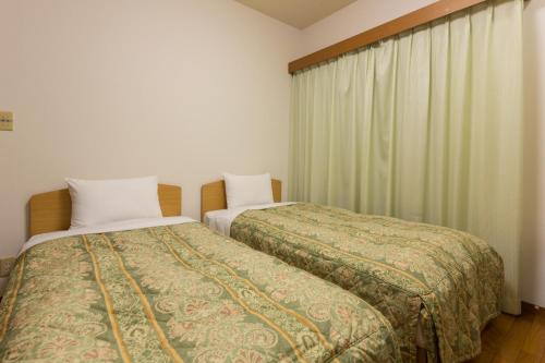 1 dormitorio con 2 camas y ventana en スイートヴィラパノーラ八ヶ岳, en Kunizakai