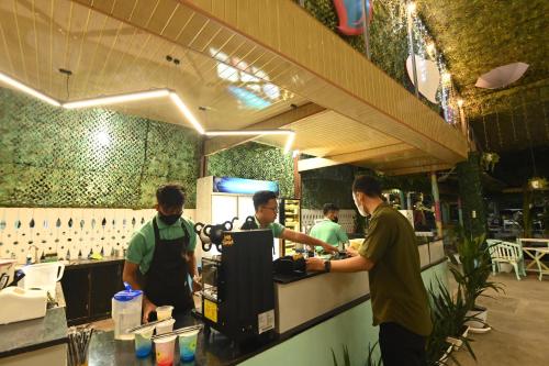a group of men standing at a counter in a restaurant at MCM HOTEL WISATA BOJONEGORO in Bojonegoro