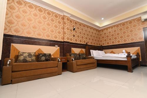 a room with a bed and two couches in it at MCM HOTEL WISATA BOJONEGORO in Bojonegoro