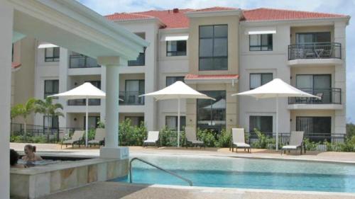 a hotel with a swimming pool and umbrellas at The Sands Unit 9 in Yamba