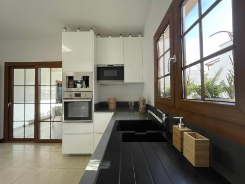 a kitchen with white appliances and a large window at Holyhome villa cinema perfect for families in Costa Teguise