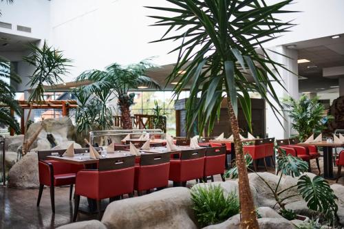 a restaurant with tables and chairs and a palm tree at Hotel Toplice - Terme Čatež in Čatež ob Savi