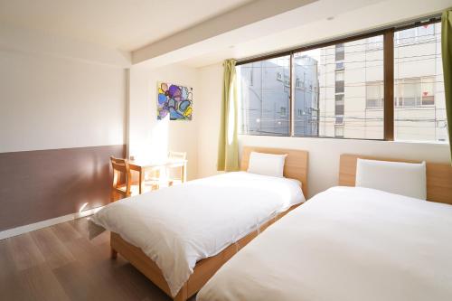 Dos camas en una habitación con ventana. en Shirakabanoyado - Doutonbori 道頓堀, SELF CHECK IN ONLY, en Osaka