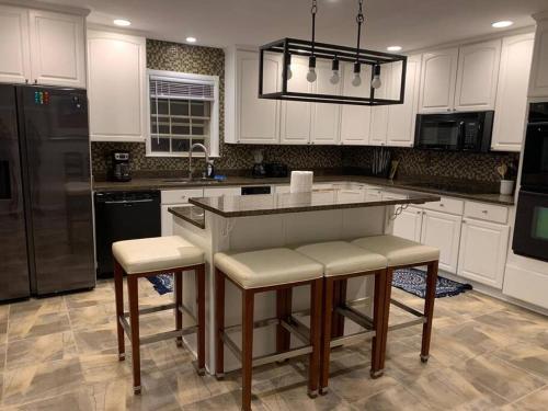 a kitchen with white cabinets and a island with bar stools at Large Southern Home with Swimming Pool, 5 king bed in Memphis