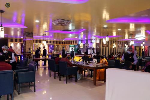 a restaurant with people sitting at tables and purple lighting at Blue Diamond Resort & Hotel in Muzaffarpur