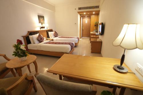 a hotel room with two beds and a table at SP Grand Days in Trivandrum
