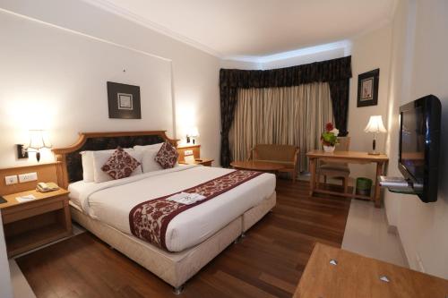 a hotel room with a bed and a flat screen tv at SP Grand Days in Trivandrum
