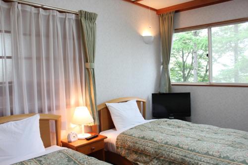忍野村的住宿－スイートヴィラ山中湖，酒店客房设有两张床和电视。