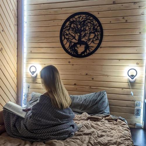 a woman sitting on a bed in front of a wall at Ecottage котедж для двох у горах із чаном-джакузі in Slavske