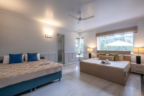 a bedroom with two beds and a couch at StayVista at The Banyan Abode with Pool Table, Pet Friendly & Outdoor Pool in Manesar