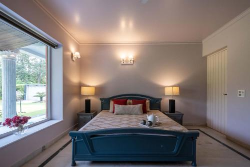 a bedroom with a blue bed with a window at StayVista at The Banyan Abode with Pool Table, Pet Friendly & Outdoor Pool in Manesar