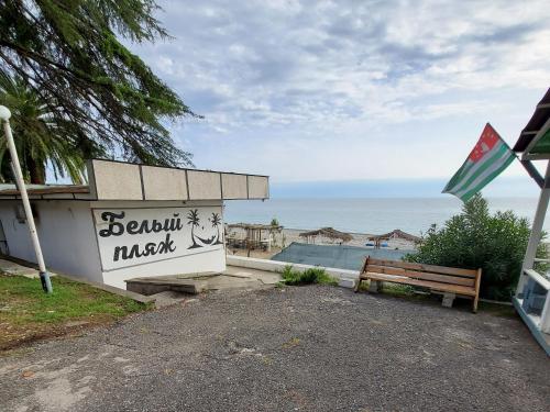 a building with a bench next to the beach at Дом с видом на море на Белом пляже in Novy Afon