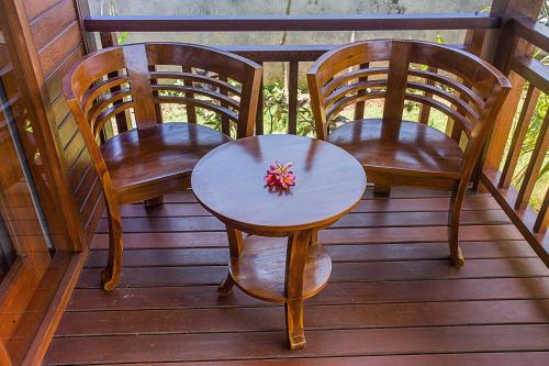 three chairs and a table on a porch at Pondooks Joglo in Nusa Lembongan