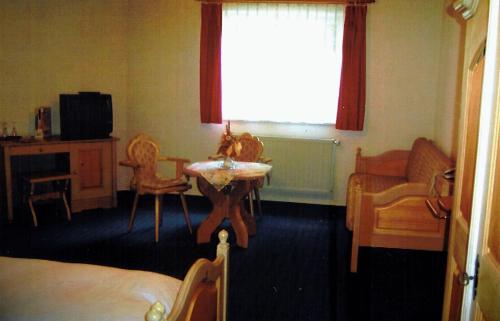 a bedroom with a bed and a table and a window at Land-gut-Hotel Zur Lochmühle in Penig