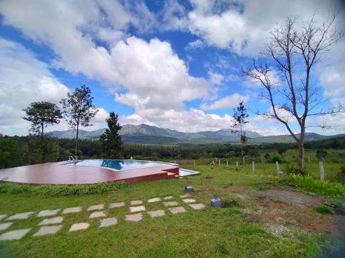a swimming pool in a field with mountains in the background at Coffeeberry Hills Chikamagalur in Chikmagalūr