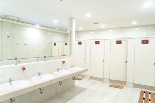 een badkamer met 3 wastafels en een grote spiegel bij Miko Rooms & Capsules hotel in Bungurasih
