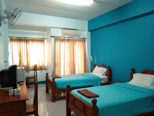 a blue room with two beds and a tv at Kasarin Court in Fang