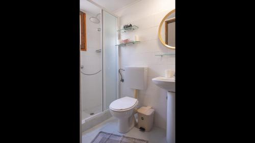 a white bathroom with a toilet and a sink at Beautiful house located on a hill, with a spectacular sea view in Koumeika