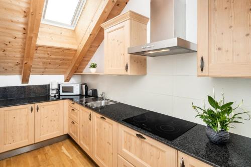 uma cozinha com armários de madeira e bancadas pretas em Fini's Apartments em Vipiteno