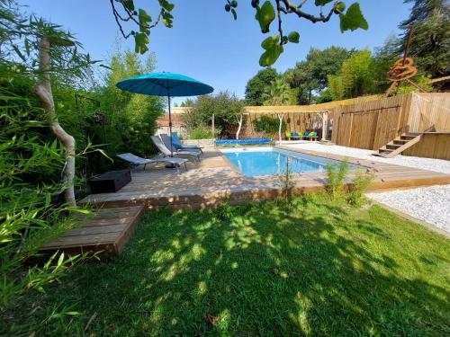 um quintal com uma piscina e um guarda-sol em La Villa Hossegor em Hossegor