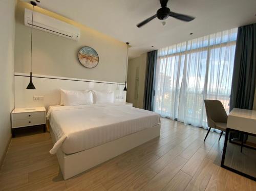 a bedroom with a white bed and a ceiling fan at Grace Samudera Hotel in Semporna