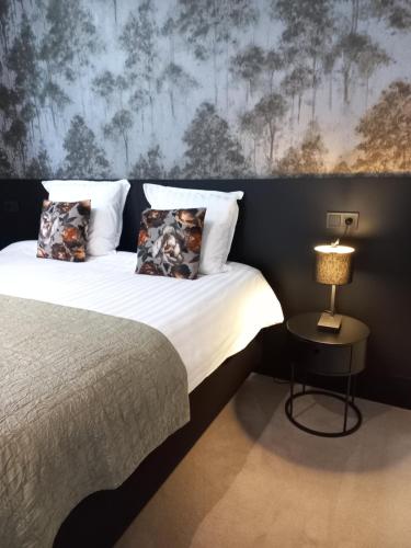 a bedroom with a large bed with a lamp on a table at Boutique Hotel De Oude Veste in Hellevoetsluis