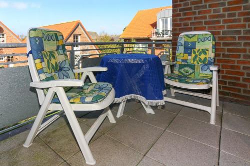 2 Stühle und ein Tisch auf dem Balkon in der Unterkunft Haus Strandlooper in Neuharlingersiel