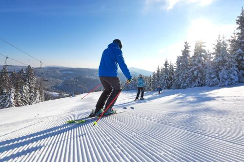 two people are skiing down a snow covered slope at Hotel Planja in Zreče