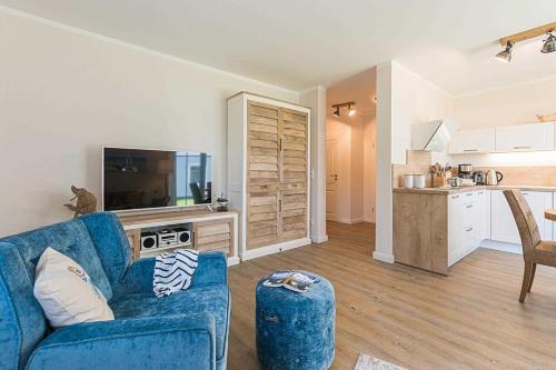 a living room with a blue couch and a kitchen at Mirabelle in Zingst