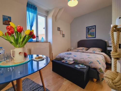 Chambres d'hôtes "Le Clos de la Baie" في بيمبول: غرفة نوم بسرير وطاولة مع ورد