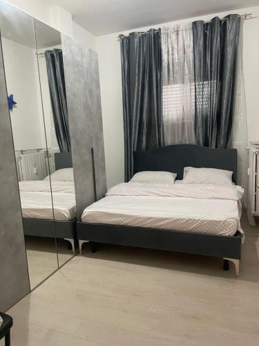 1 dormitorio con 2 camas y espejo en Appartamento Mire&Geo, en Voghera