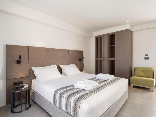 a bedroom with a large white bed and a chair at Kakkos Beach Hotel - Adults Only in Ierápetra