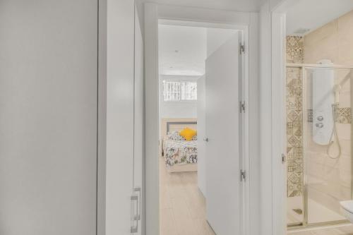 uma casa de banho com paredes brancas, um chuveiro e uma cama. em MILLION APARTAMENT em Málaga