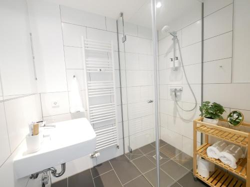 a white bathroom with a sink and a shower at Zentral, modern, gemütlich mit Balkon & Parkplatz in Paderborn