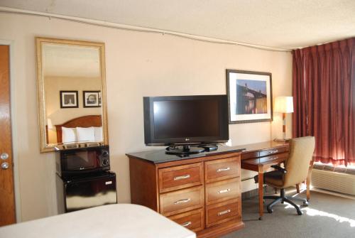 a hotel room with a desk with a television and a bedroom at Inn at the Convention Center in Portland