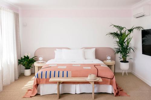 a bedroom with a bed and two plants at Motel Molly - Boutique Hotel Mollymook in Mollymook