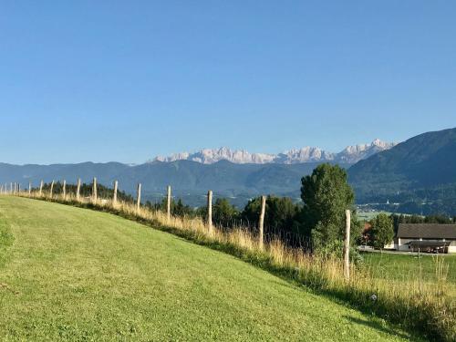 a field with a fence and mountains in the background at Haus Romsicht Karinthië in Kerschdorf