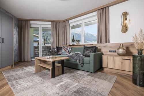 a living room with a green couch and a table at Hotel Viktoria & Landhaus Joggl in Mayrhofen