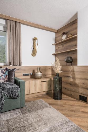 a living room with a green couch and a window at Hotel Viktoria & Landhaus Joggl in Mayrhofen
