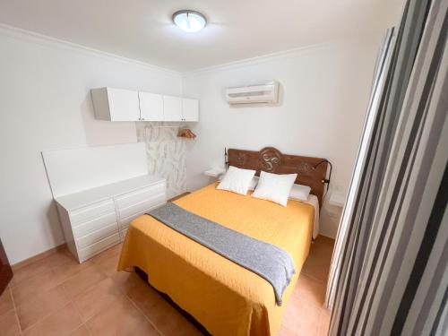 Dormitorio pequeño con cama con manta amarilla en Home2Book Ático Blue Beach, Pool&Terrace, en Sardina