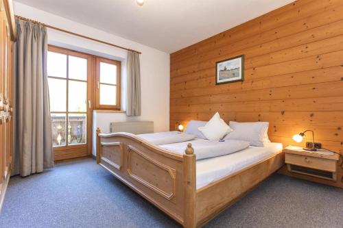 ein Schlafzimmer mit einer Holzwand mit einem Bett und einem Fenster in der Unterkunft Haus Pfistererbauer in Brixen im Thale