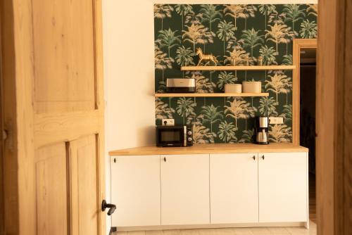 una cucina con armadi bianchi e carta da parati con piante di Vakantiewoning Dorp-28 a Hollebeke