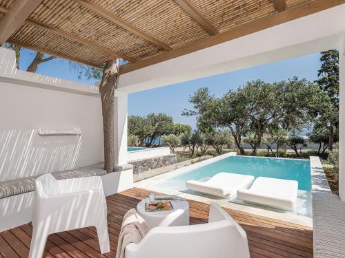 a patio with a pool and white furniture at Kakkos Bay Hotel and Bungalows in Ierápetra