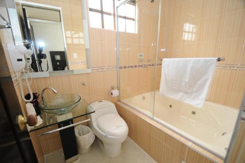 a bathroom with a toilet and a tub and a sink at Villeta Boutique Hotel Spa in Villeta