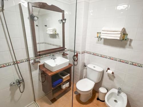y baño con aseo, lavabo y espejo. en Home2Book Ático Blue Beach, Pool&Terrace, en Sardina