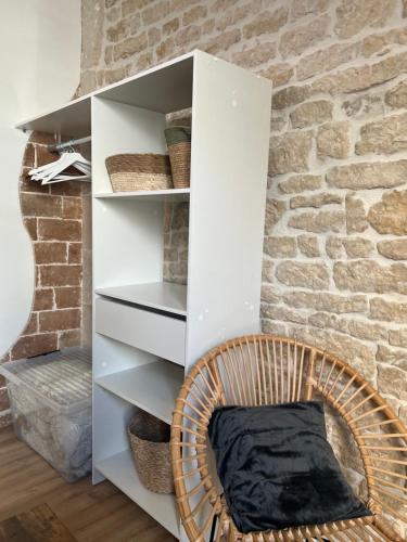een rieten stoel in een kamer met een bakstenen muur bij Le Bjorn - T1 chaleureux refait à neuf - Centre in Niort