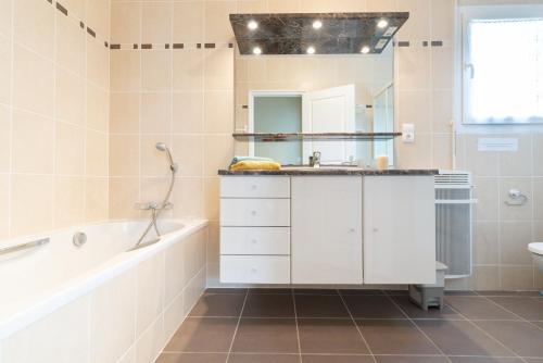 a bathroom with a tub and a sink and a bath tub at Le Chemin Vert - maison avec piscine in Matignon