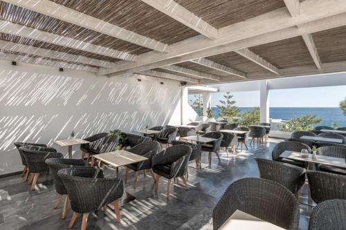 a restaurant with tables and chairs and the ocean at Kakkos Bay Hotel and Bungalows in Ierápetra