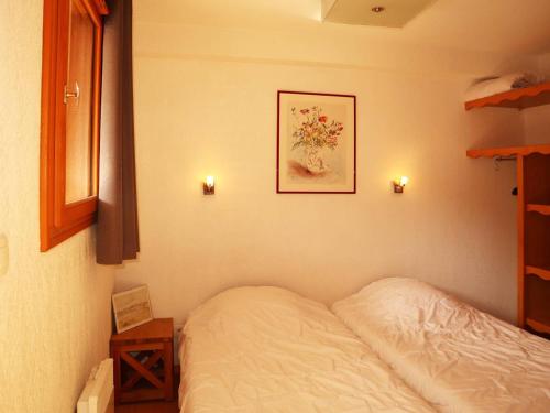 un lit dans une chambre avec un tableau sur le mur dans l'établissement Appartement skis aux pieds avec piscine intérieure, proche services - FR-1-322-478, aux Orres