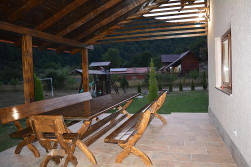 a wooden picnic table and benches on a patio at cabana din padure in Finiş